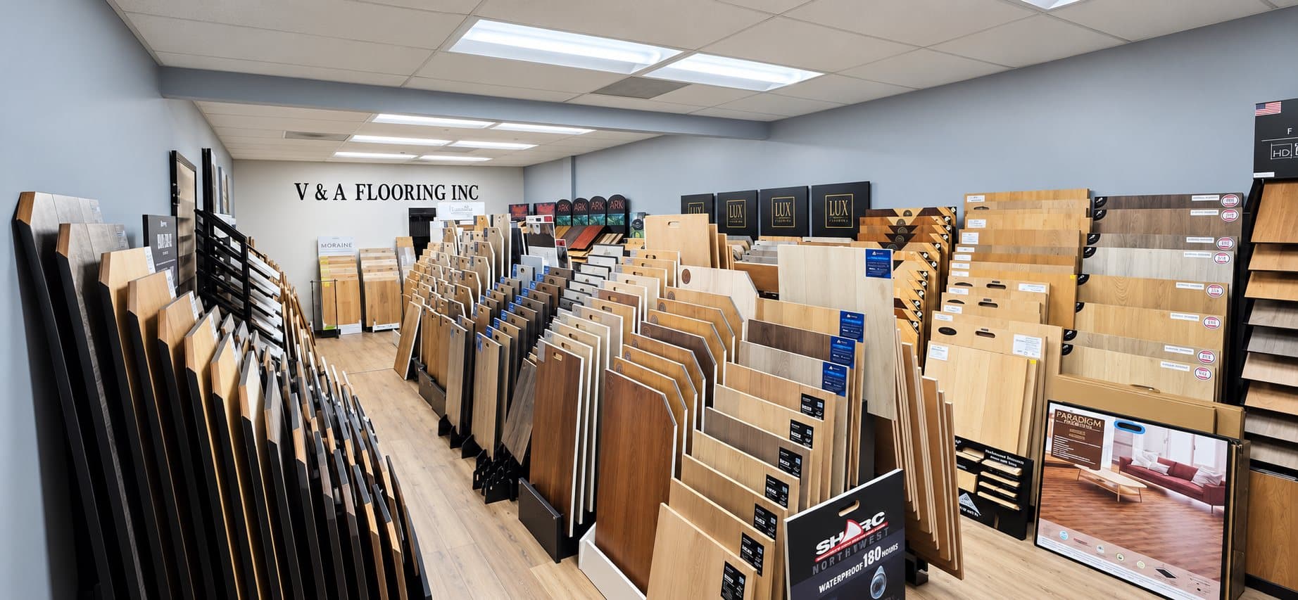 V & A Flooring Inc showroom with racks of hardwood, laminate and vinyl plank samples